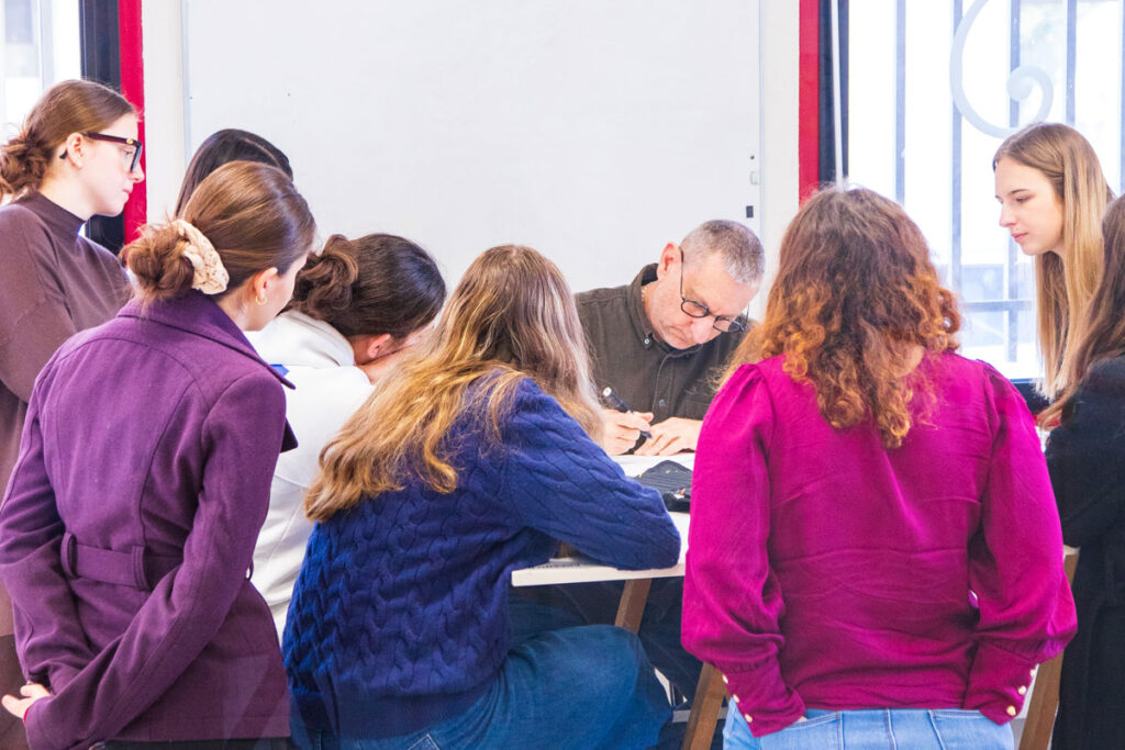 Étudiantes en Graphisme observant leur enseignant réaliser un croquis.